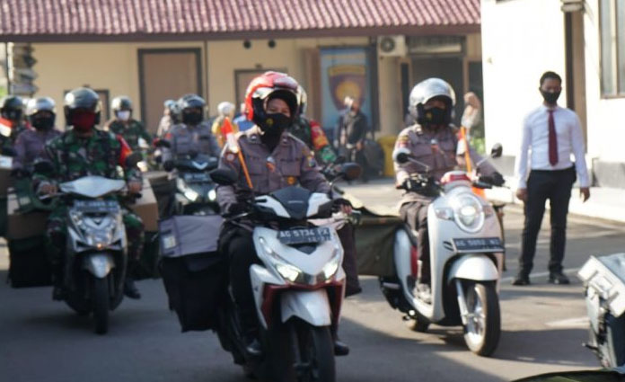 Sejumlah petugas gabungan yang terdiri dari anggota Polres Blitar Kota bersama dengan anggota TNI, Forkopimda Kota Blitar dan Kabupaten Blitar, melakukan konvoi sepeda motor sambil membagikan sembako bagi masyarakat/Jumat (26/6)